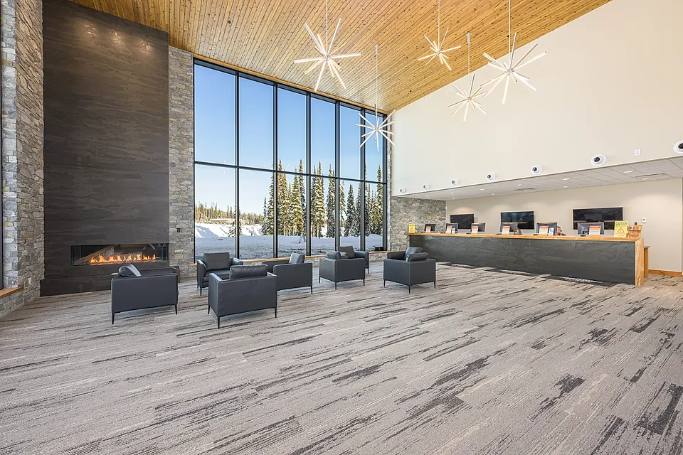Big White Central Reservations reception interior with timber ceilings, stone fireplace and full-height windows